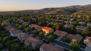 Aerial view of a Yorba Linda-style suburban neighborhood at golden hour, with one home lit apart from the rest, illustrating how Yorba Linda Mello-Roos applies to specific parcels.