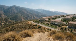 Dry chaparral hillside meeting a cleared buffer and tile-roofed hillside homes in an Anaheim Hills fire hazard zone